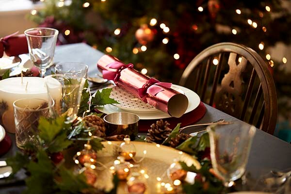 Table setting with a Christmas cracker arranged on a plate.
